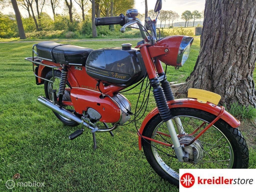 Rode Kreidler floret op grasveld. Je brommer start niet, Kreidlerstore lost het op.